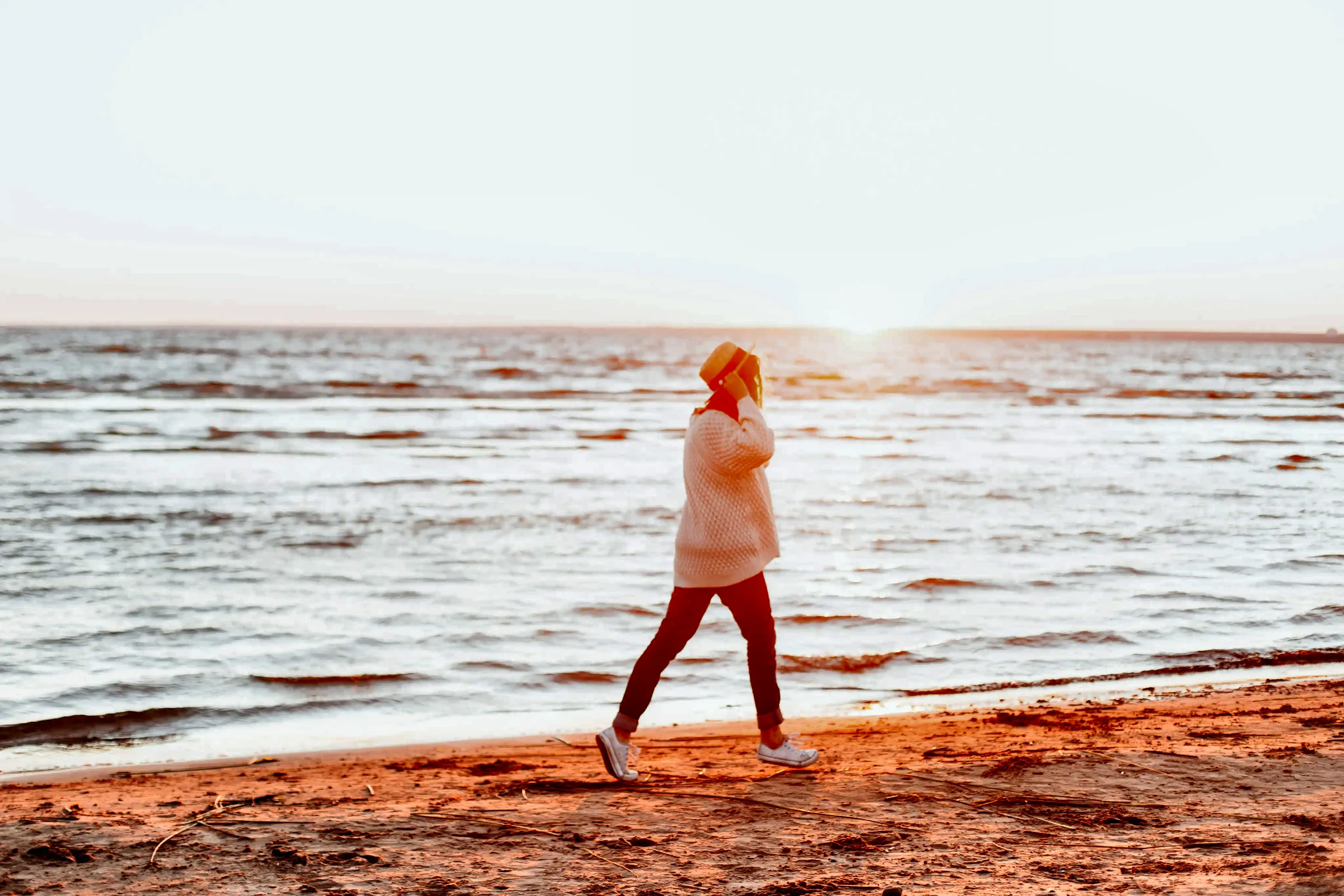 Woman walking on the beach at sunrise after bioidentical hormone therapy in Charleston